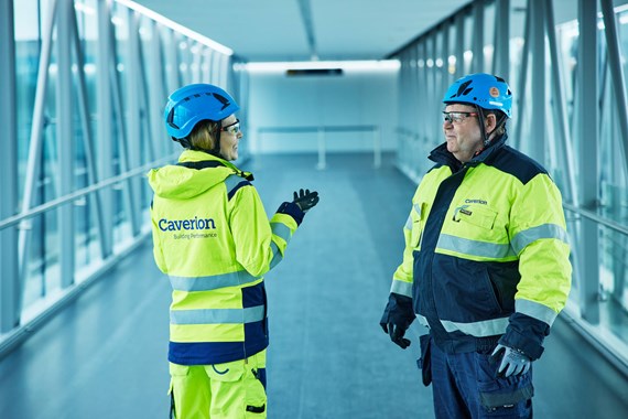 To caverion medarbeidere ser på en iPad og smiler