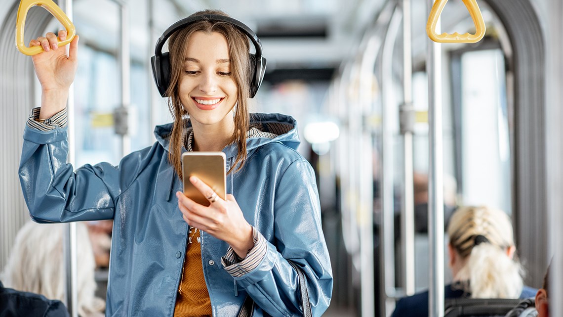 Ung kvinne ser på mobilen mens hun reiser kollektivt